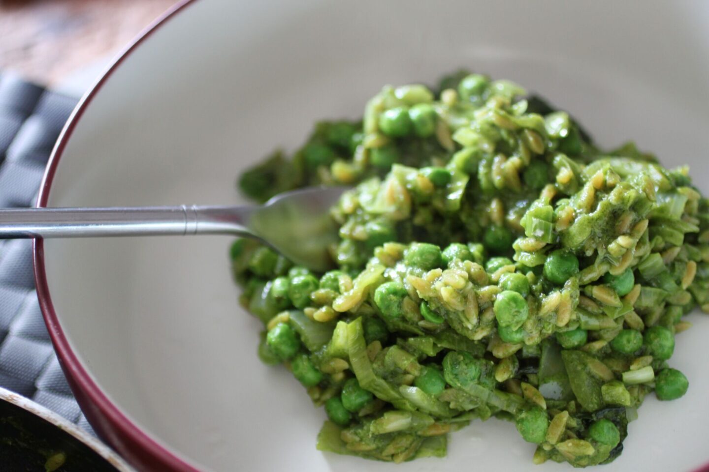a bowl of orzo risotto with a fork in it