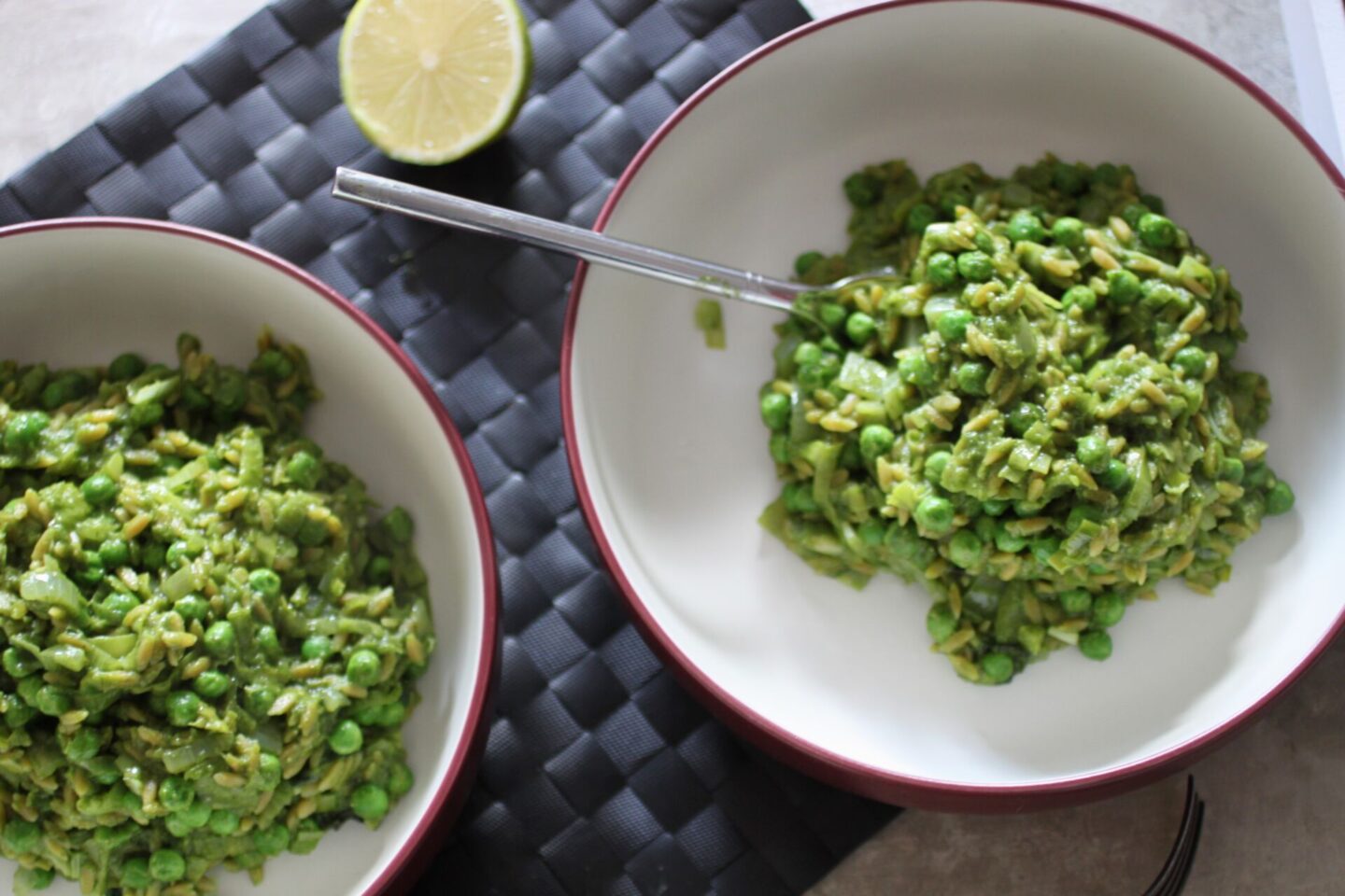 two bowls of pea & basil orzo risotto placed on a table, shot from above