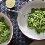 two bowls of pea & basil orzo risotto placed on a table, shot from above