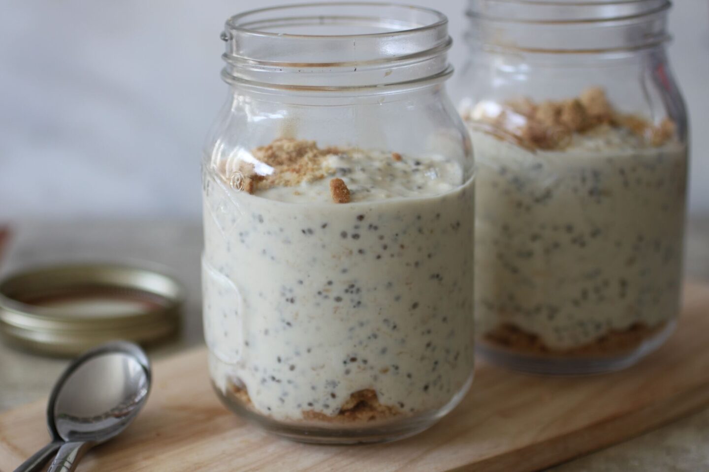 two pots of ley lime pie overnight oats on a wooden board with spoons placed next to them