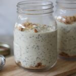 two pots of ley lime pie overnight oats on a wooden board with spoons placed next to them