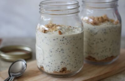 two pots of ley lime pie overnight oats on a wooden board with spoons placed next to them