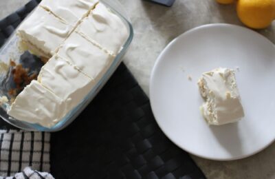 lemon tiramisu on a table, placed next to a plate with a serving of tiramisu next to it