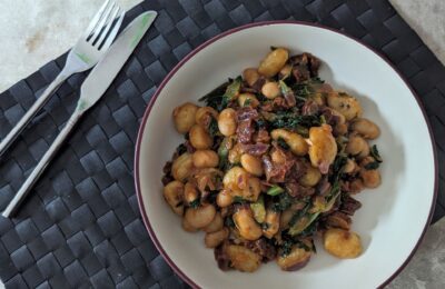 bowl of Tuscan bean gnocchi on a table with a knife and fork