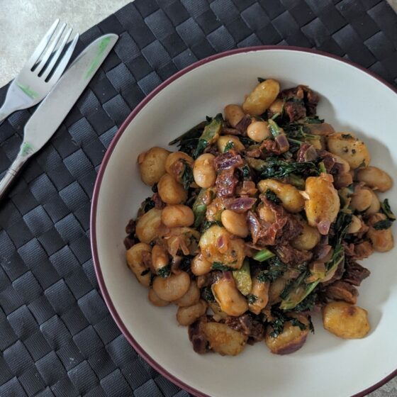 bowl of Tuscan bean gnocchi on a table with a knife and fork