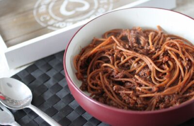 a bowl of vegan ragu placed on a table with some cutlery