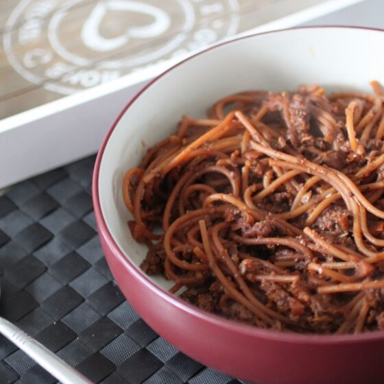 a bowl of vegan ragu placed on a table with some cutlery