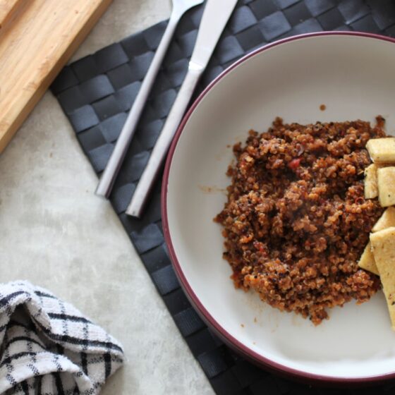 bowl of beetroot quinoa with crispy salt and pepper tofu placed on a black table mat, shot from above