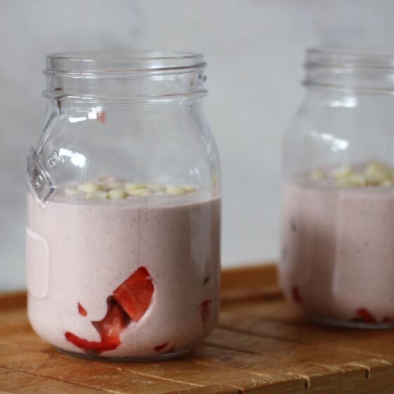 two jars of strawberry blended overnight oats on a wooden tray