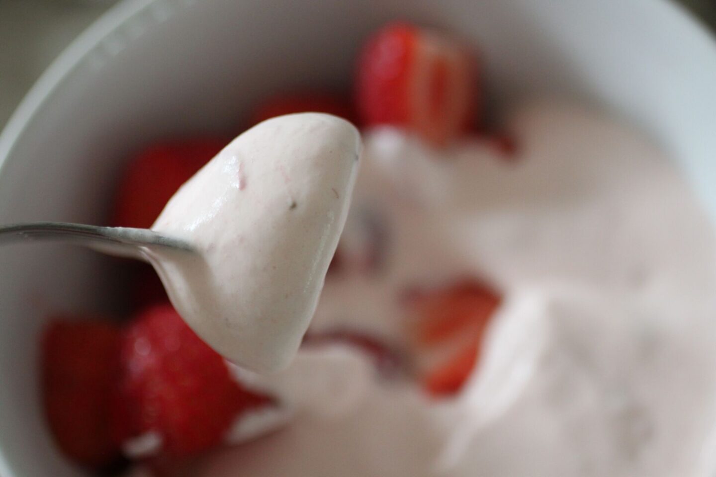 a strawberry on a fork covered in strawberry cream