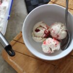three scoops of strawberry swirl ice cream in a white bowl