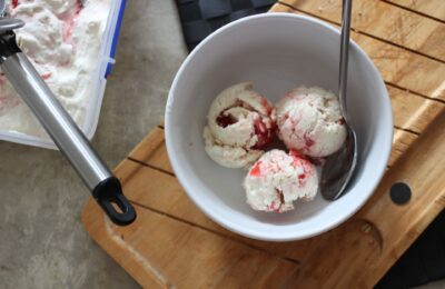 three scoops of strawberry swirl ice cream in a white bowl