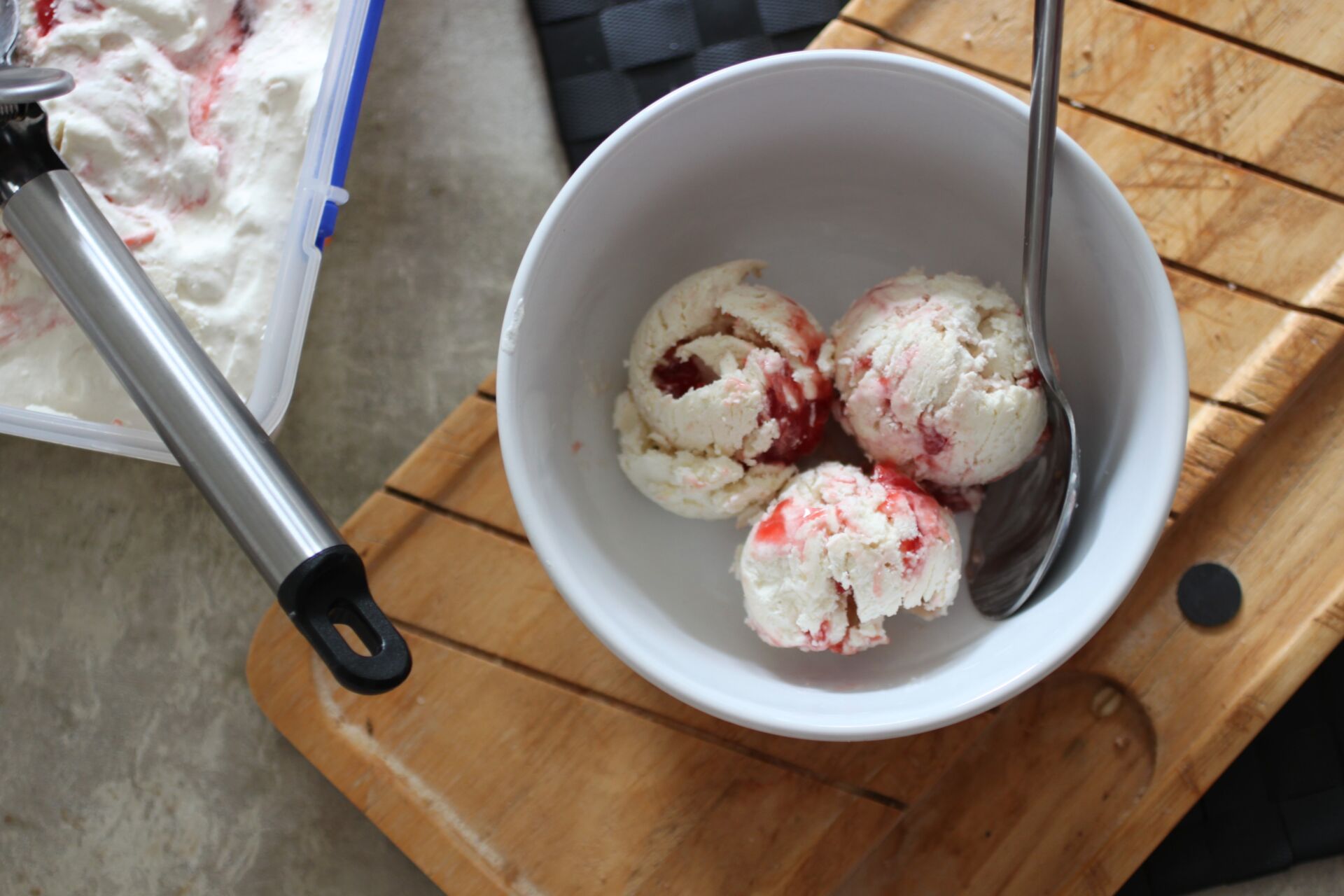 three scoops of strawberry swirl ice cream in a white bowl