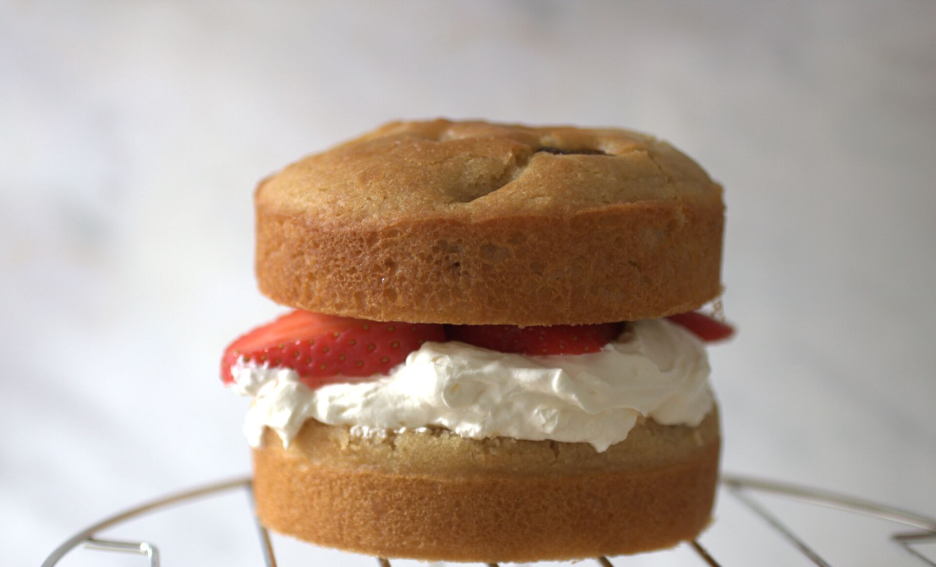 strawberry cream cake on a cooling rack