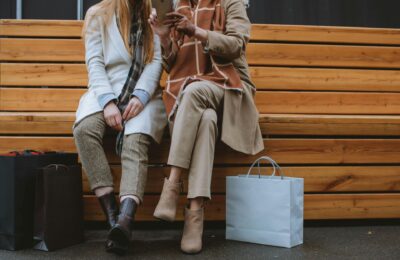 two women wearing trousers sat on a bench