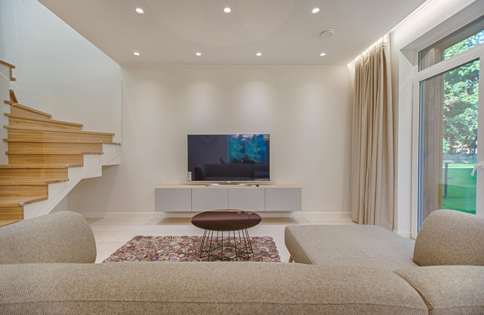 TV room with neutral decor and open staircase