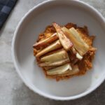 bowl of creamy carrot dip topped with maple roasted parsnips, shot from above