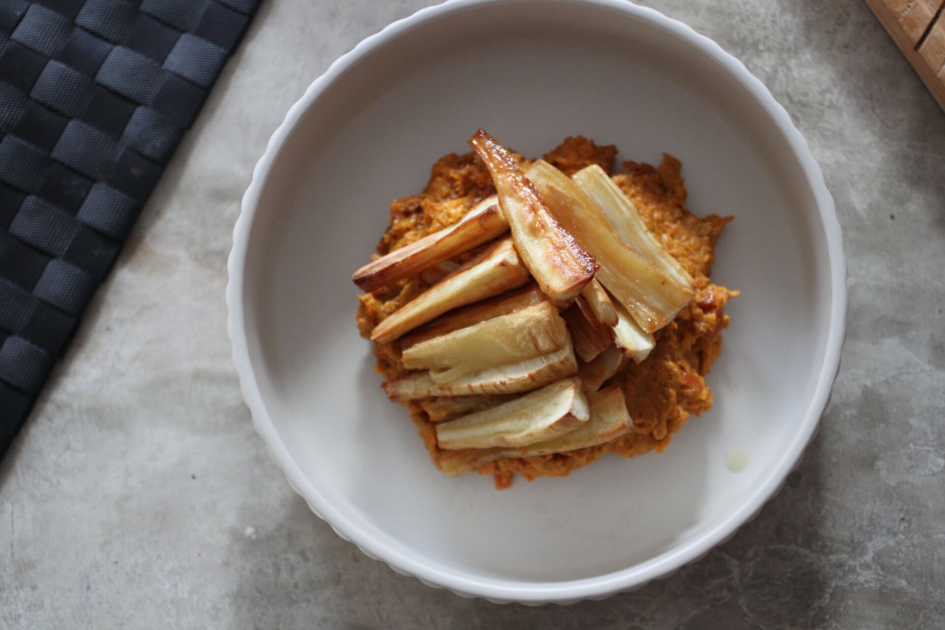 bowl of creamy carrot dip topped with maple roasted parsnips, shot from above