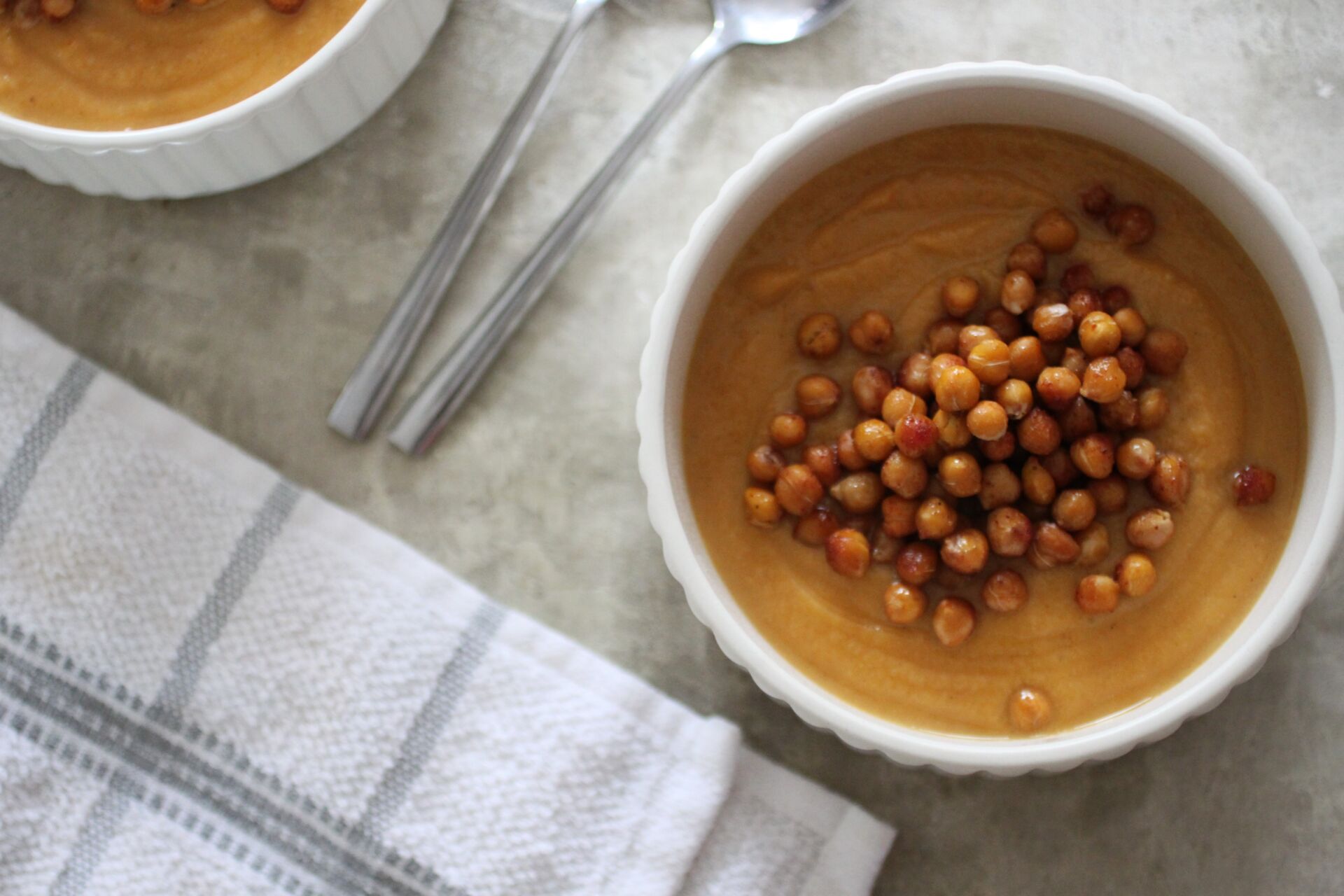 two bowls of spiced sweet potato soup topped with chickpeas