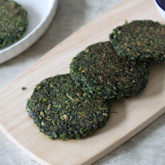 wooden board with purple sprouting broccoli and kale fritters on