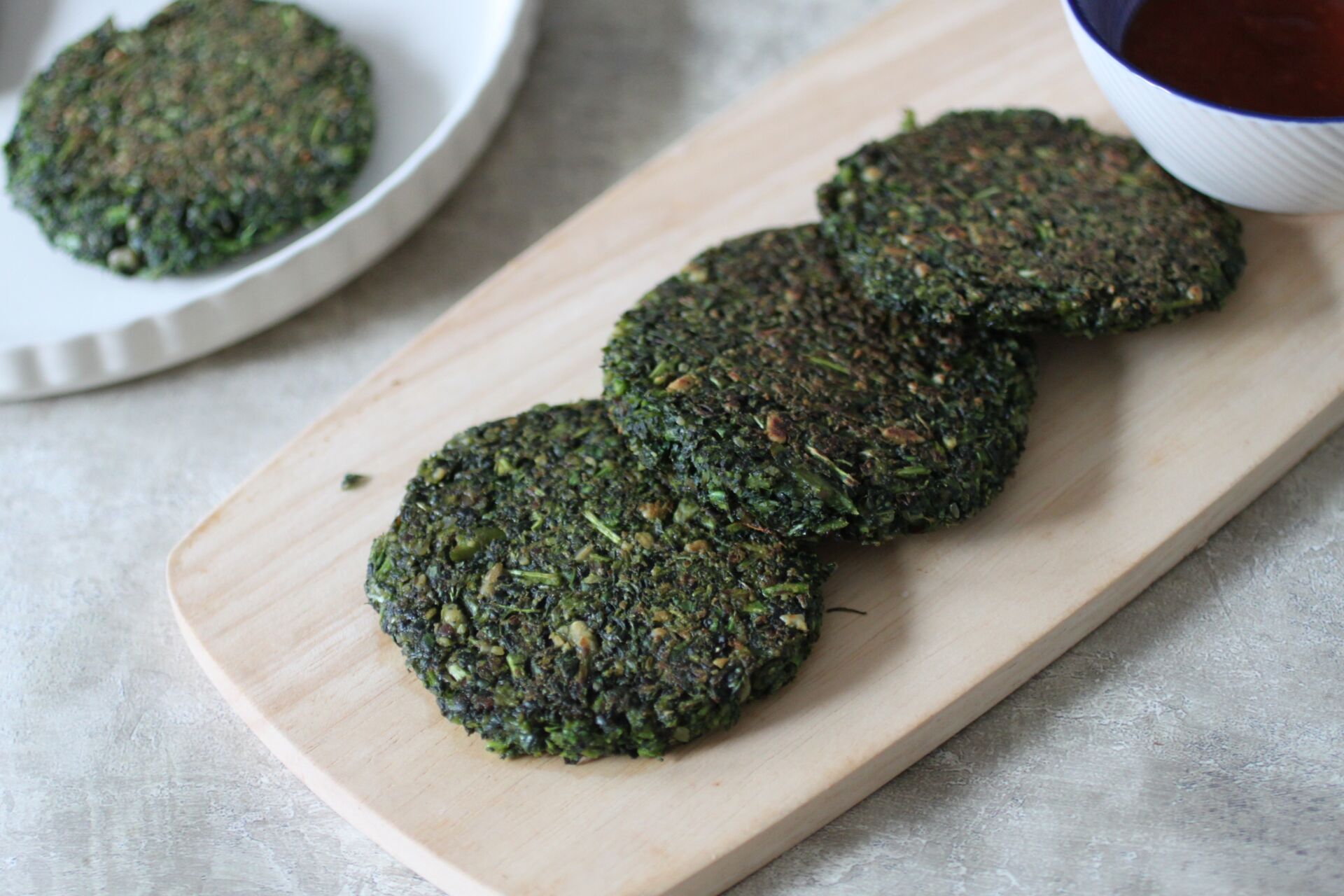 wooden board with purple sprouting broccoli and kale fritters on