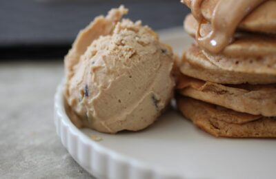 a scoop of peanut butter choc chip ice cream next to a stack of peanut pancakes