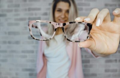 woman holding a pair of glasses to the camera