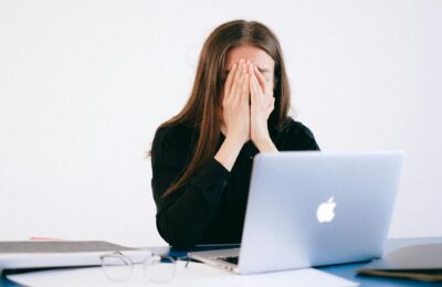 woman sat at desk with head in hands