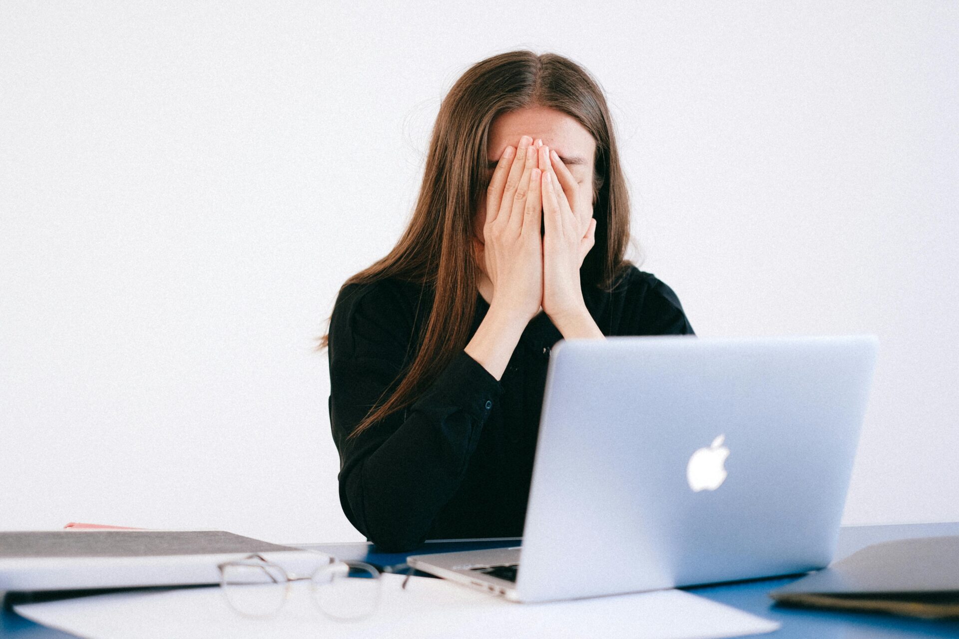 woman sat at desk with head in hands