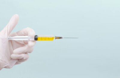hand wearing white glove holding an injection