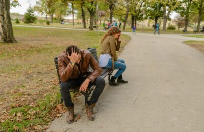 a couple arguing on a bench in a park